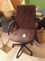Brown upholstered office chair showing front view with wooden armrests and wheels.