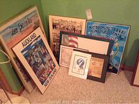 Overview of all seven art pieces leaning against green wall on carpet.