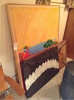 Three paintings leaning against wall: large yellow-orange canvas at back, medium and small canvases in front