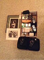 Overview of the cameras, walkie talkies in case, and two framed photos on carpeted floor.