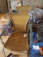 Pair of chairs with iron frames and plastic wicker seats and backs, showing overall condition and design.