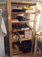 Full view of wooden shelving unit containing multiple boxes and tool items.