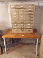 Full view of pine tabletop with metal legs and steel cabinet on top