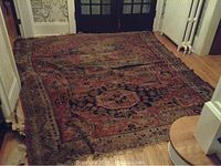 Full view of the large Oriental rug laid out on hardwood floor showing overall design and condition.