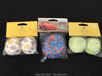 Three packages of baking cups shown: Pixar Cars 2-inch cups, one package each of two different mini cup designs
