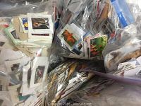 Multiple resealable plastic bags containing large quantities of trimmed used postage stamps, stored in a box.