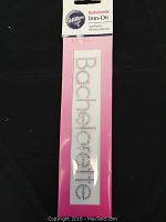 Photo of Wilton brand Bachelorette iron-on rhinestone applique in original packaging, showing packaging and applique spelling 'Bachelorette' vertically.