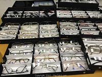 Close-up showing multiple trays each holding various eyeglass frames with different frame styles and colors.