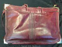 Full front view of a burgundy leather briefcase showing the entire front surface with slight wear mark and metal corners.