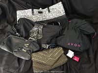 Full lot showing Dalila clutch set, gold beaded clutch, Guess handbag, Avon black fabric bag, pink interior visible, and Avon ring in box