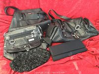 Five black bags consisting of three handbags and two clutches placed on a red background.