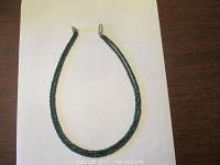Emerald bead necklace laid in U-shape on white paper over wood surface