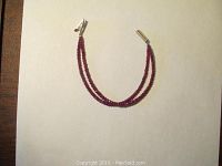 Full view of double-strand ruby bead bracelet laid on white background
