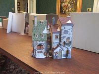 Front view of hand-painted porcelain Dickens Village building showcasing detailed roof and windows.