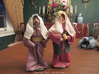 Two male Byers Choice Caroler figurines standing on a wooden table, shown from front.