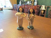 Photo of two Indian Byers Choice Carolers on green bases displayed on a table in a dining room.