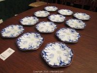 Twelve octagonal blue and white dessert plates arranged on a table showing overall lot.