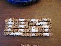 Ten pieces of stone-textured fencing arranged neatly on a wooden surface showing stone design and snow patches.