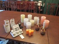 Wide shot of all battery operated candles of different colors and sizes along with the Viatek LED tea-lights charging base, remote, and glass votives.
