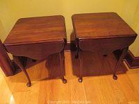 Photo showing two matching wooden end tables with drop-leaf sides in closed position, medium brown finish, cabriole legs with ball-and-claw feet.