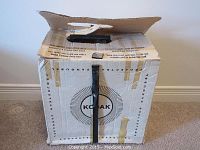 Original Kodak Carousel projector box with visible wear and tape repairs, white color with Kodak logo.