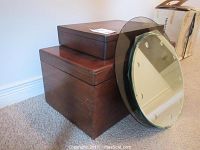 Two wooden lidded boxes stacked; smaller box atop a larger one with a round glass tabletop leaning against them, showing front view and sizes.