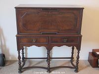 Front view of entire desk showing drop-front panel closed, drawer configuration and leg style