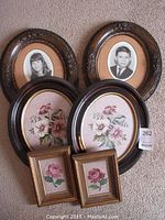 Six pieces in the lot arranged on floor: 2 oval framed black and white child portraits, 2 large oval framed floral needlepoint art, 2 smaller rectangular framed floral needlepoint art