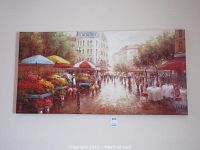 Front view of large rectangular canvas print depicting a street scene with outdoor cafes, umbrellas, flowers, and pedestrians.
