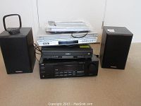 Front view of the stereo components stacked with remotes and manuals on top: Insignia silver CD player, JVC RX-668V receiver, JVC DVD/VCR combo, Paradigm bookshelf speakers flanking sides.