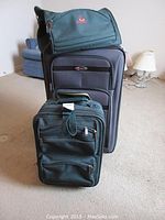 Front view of all three luggage pieces stacked in descending size order, showing colors and branding.