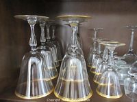 Clear glass wine glasses with gold rim and tall stems arranged in rows