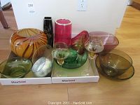 Full lot of decorative glass vases and bowls showing the variety of colors and styles including amber, pink, purple, green, black glass pieces.