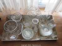 Full overhead view of the large mixed glassware serving lot showing multiple items including candle holders, bowls, plates, pitcher, lidded dish, and trays with various pressed glass patterns.