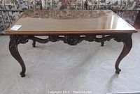 Front view of wood coffee table with glass top and carved leg details
