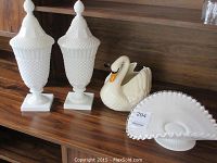 Photo showing matching pair of white milk glass hobnail lidded vases, ceramic swan planter, and one ruffled edge decorative glass bowl.