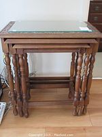 Front view of the nested tables stacked together showing size progression and turned legs.