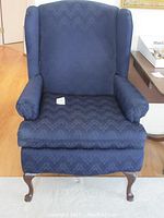 Front view of blue patterned wingback chair showing fabric and legs.