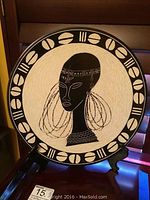 Front view of 14 inch Kenyan decorative plate on stand showing African woman profile and border motifs.