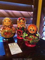Three sets of wooden Russian nesting dolls displayed on a table; showcasing variety in size and decoration