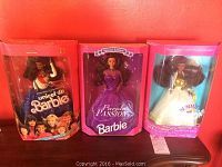 Three special edition Barbie dolls in original boxes displayed against a red background: UNICEF Barbie, Purple Passion Barbie, and Summit Barbie.