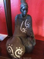 Front view of large wooden figurine showing painted white swirls and dots on robe and wrapped head.