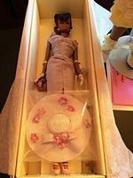 Barbie Fashion Model Collection Sunday Best doll lying in original box with white hat decorated with small lavender flowers in plastic bag, wearing fitted lavender dress and white gloves.