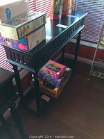 Full view of wood console table showing length, shape, and items on top for scale.