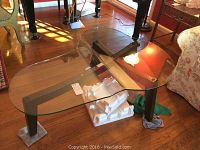 View showing the piano-shaped clear glass top and wooden legs with floor pads for protection