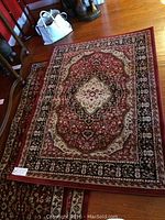 Area rug with intricate oriental medallion floral pattern in red, black, cream, and beige tones.
