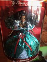 Full view of a Holiday Barbie in a green and silver dress with red ribbon and floral decorations inside original box.