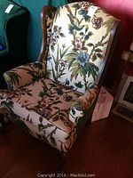 Front view of the wingback chair showing floral fabric on seat, arms, and front backrest, wooden feet and sides.