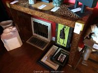 Photo showing the full laminate sofa table with leopard print top, with some objects on and around it for scale. The table is rectangular and elevated, with a vent-like feature on one vertical face.