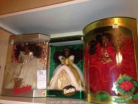 Photo showing three Special Edition Holiday Barbies in original boxes, each dressed in distinct holiday-themed gowns (white, white and gold cape, red).